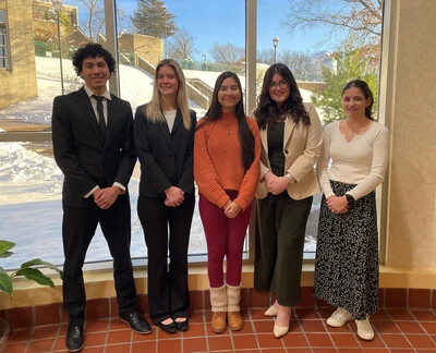 5 honors college students in front of window with snow outside