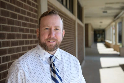 derek weber in front of brick building