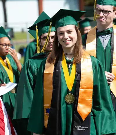 female honors college grad with other grads outside