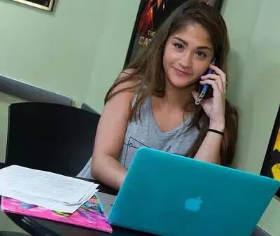girl on phone with teal laptop