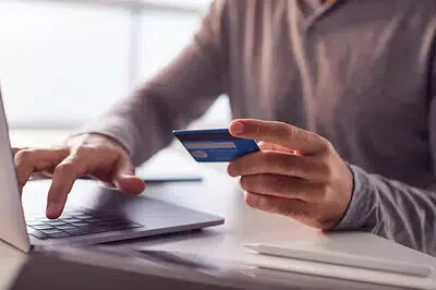 man holding credit card and typing on laptop