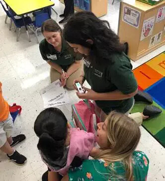 3 emale students in preschool classroom with child