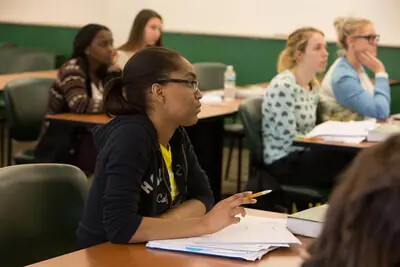 student writing in classroom with other students