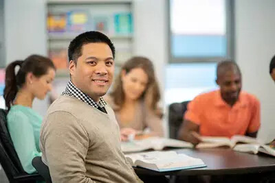 smiling maleadult with open book in meeting around table