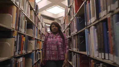 young woman walking between library shelves