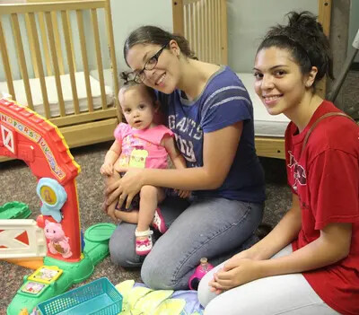 2 female adults and toddler in pink outfit