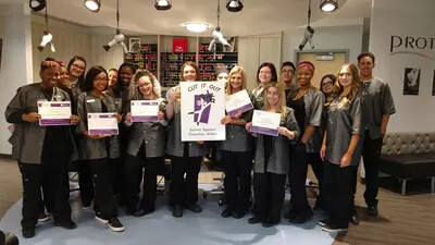 cosmetology students with cut it out sign