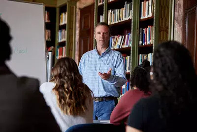 male fisher college professor in classroom with students