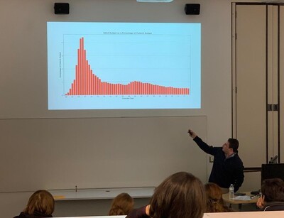 male student pointing to graph on slide projected above