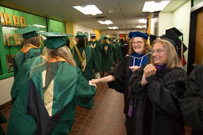 professor clutching hand of passing grad in line