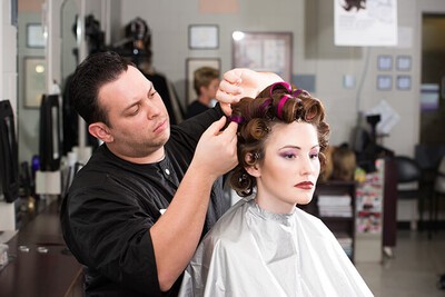 male student working on model's hair in rollers