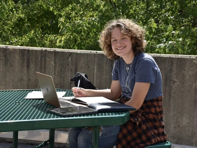 RVCC student smiling for a photo while sitting on a bench studying.