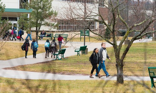 students walking outside with West Building in background