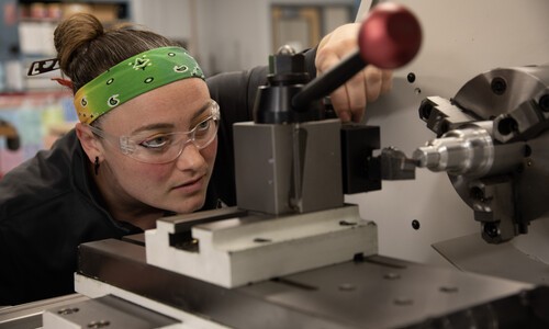 female manufacturing student with green bandana headband