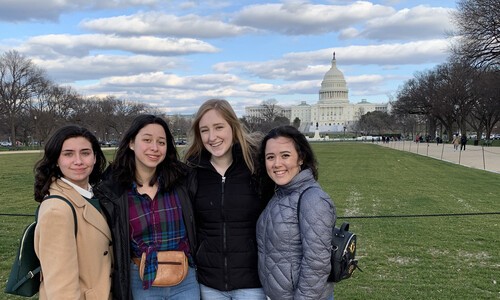 four female students with capitol in distance behind them