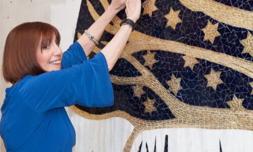evelyn rauch with hands raised to artwork with stars