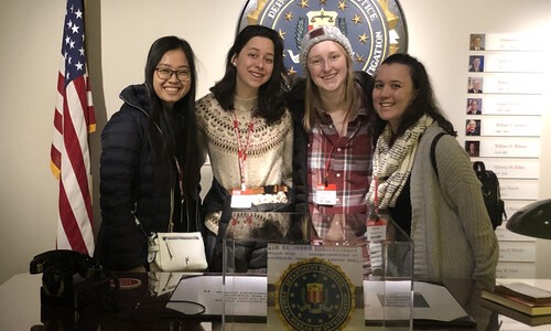 four female students with state seal and flag