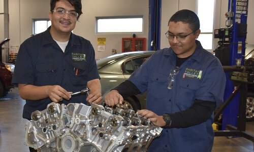 2 male students wearing glasses working on engine