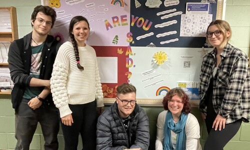 students in front of colorful bulletin board