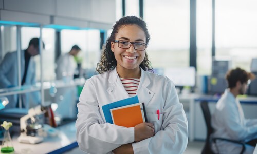 young female scientist in white lab coat holding textbooks