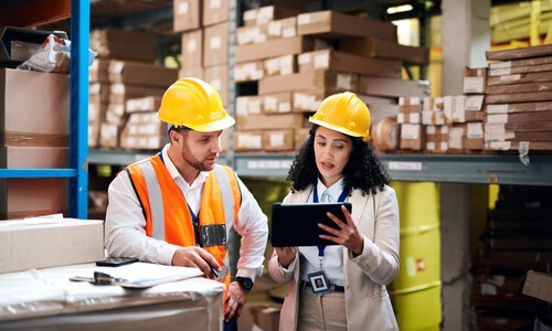 woman and man in yellow hardhats in warehouse