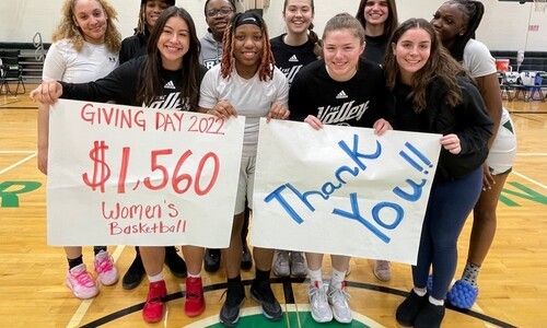 female students in gym holding giving day and thank you signs