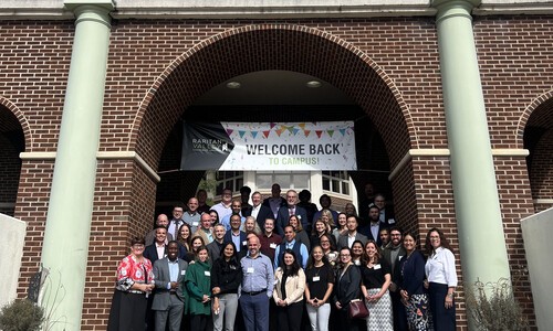 large group of people under front arches with welcome back sign