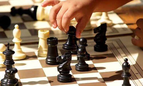 child's hand playing chess