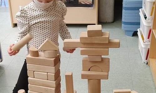masked child playing with block tower