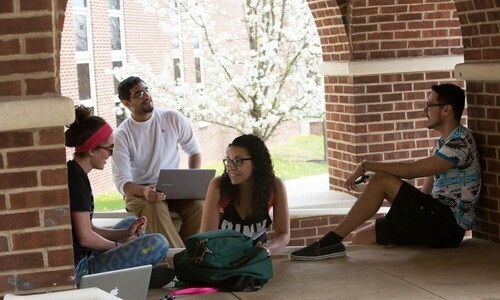 students sitting outside under under arches