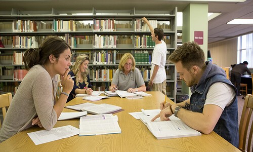 students studying around table in library