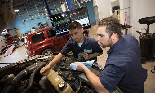 two auto tech students working on car