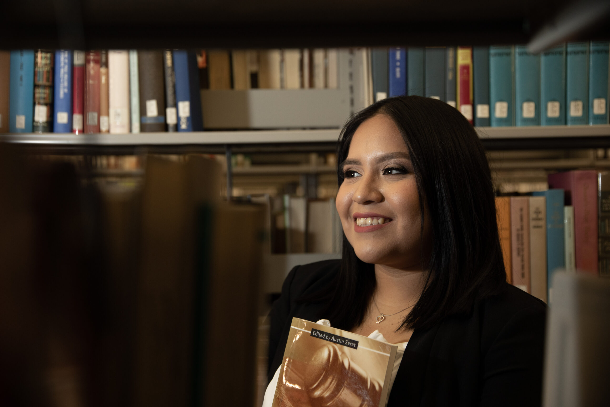 Image of an RVCC student standing in front of books in the library.