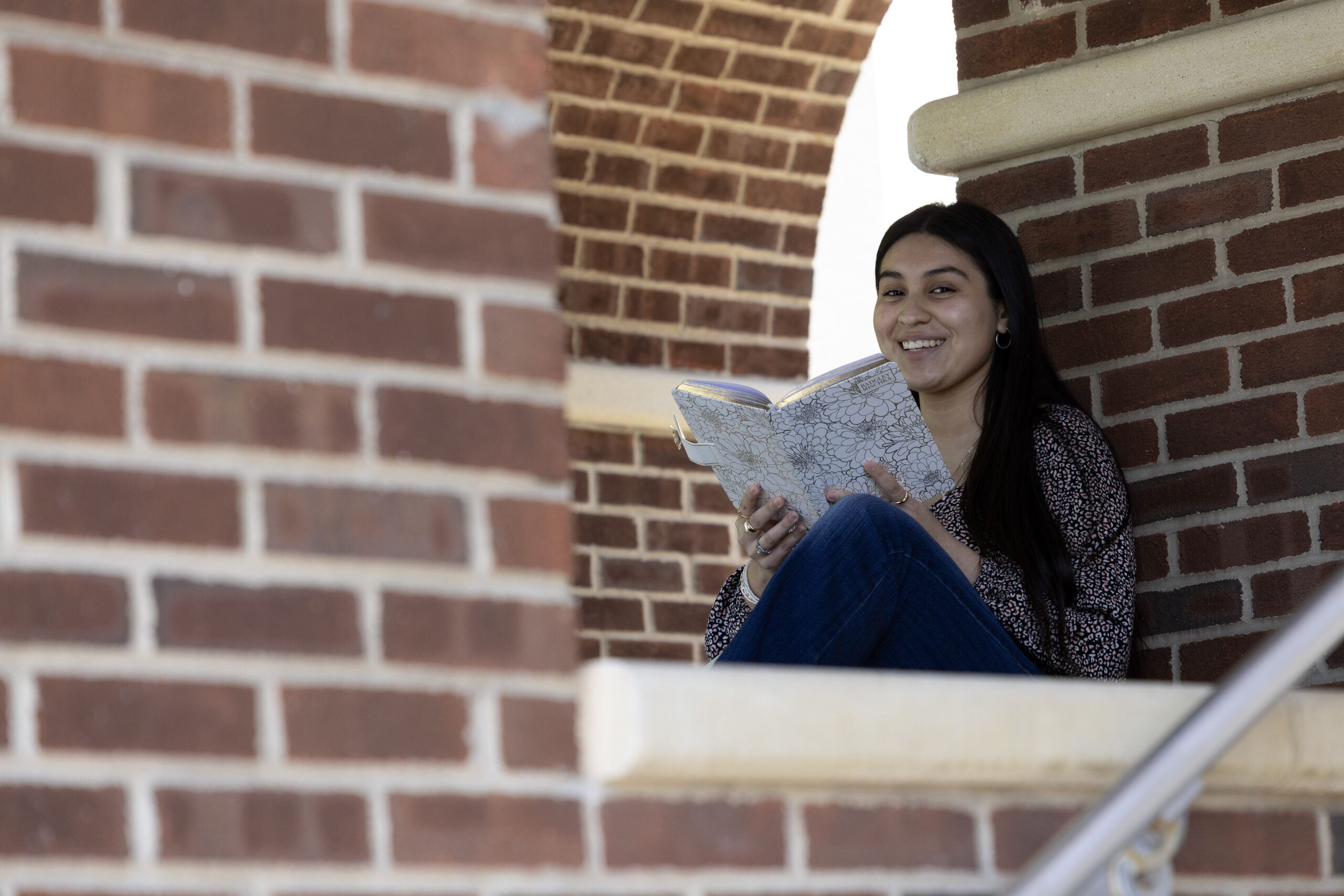 Image of an RVCC student sitting on the front steps, reading a book.