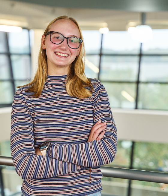 Image of an RVCC student standing on the upper level of the cafeteria with windows behind them.