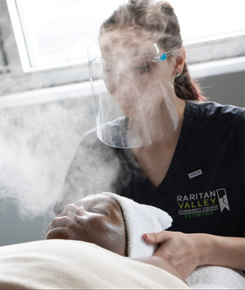 Esthetics students giving a client a facial using steam