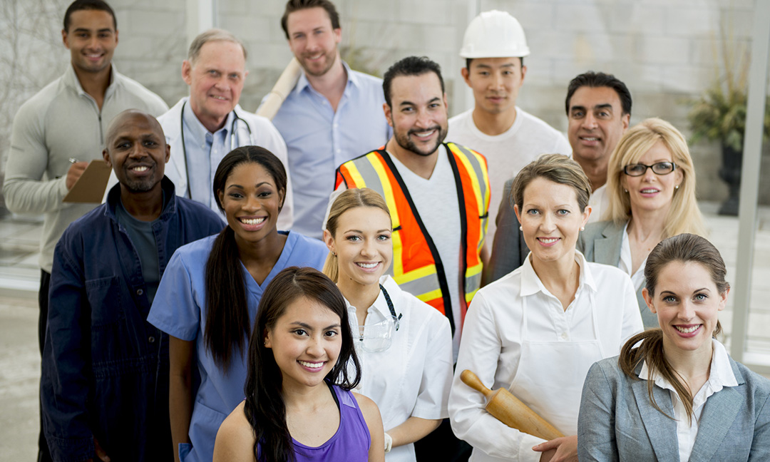 A multi-ethnic group of mixed professionals standing together in their work attire.