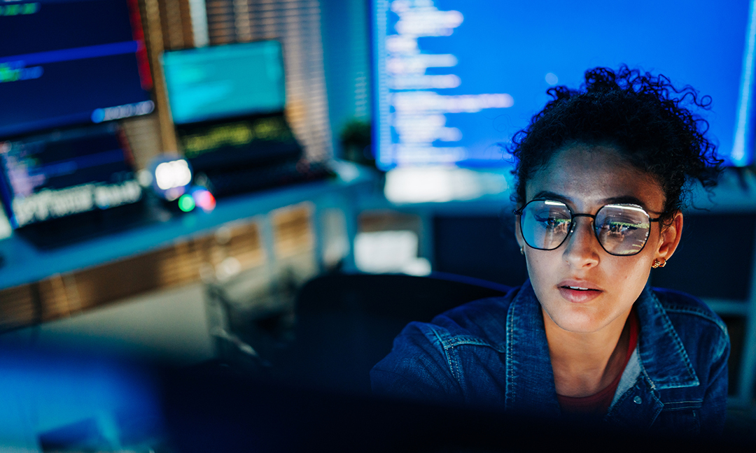 Focused Hispanic female programmer working with code in tech office