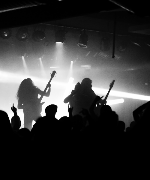 Image of a rock band playing on a stage at a small theatre.