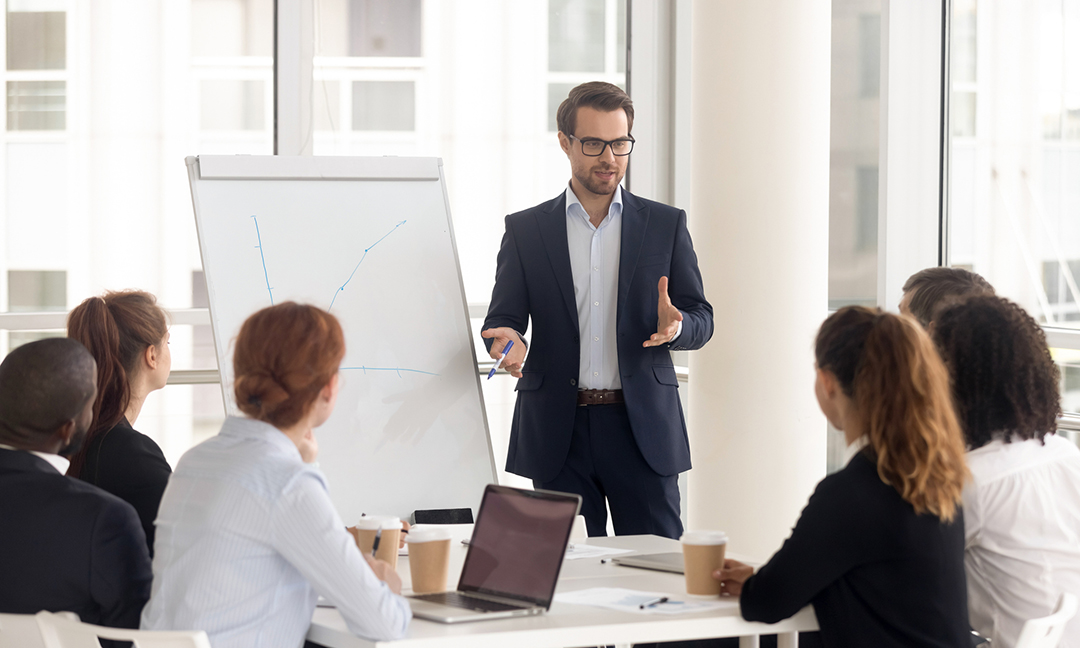 Male business coach speaker in suit give flipchart presentation, speaker presenter consulting training persuading employees client group, mentor leader explain graph strategy at team meeting workshop
