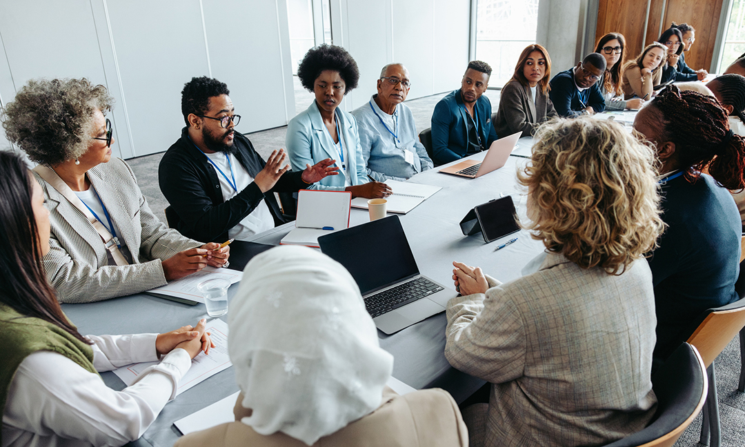 Multiethnic group of businesspeople engaged in a strategy and brainstorming session around a conference table. Collaborative and focused on teamwork and planning.