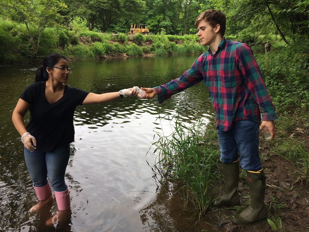 rvcc ces intern passing water sample to another intern