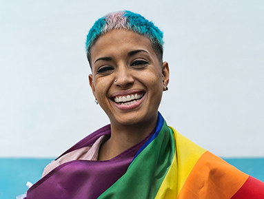 person smiling wearing flag with multicolor stripes