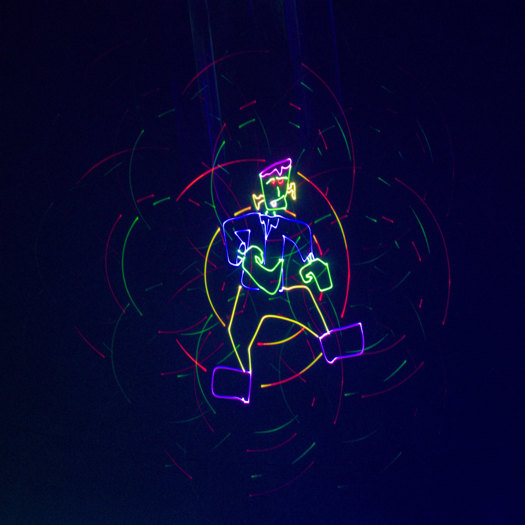 Colorful neon outline of Frankenstein dancing against a dark background with swirling red, green, yellow, and purple lights.