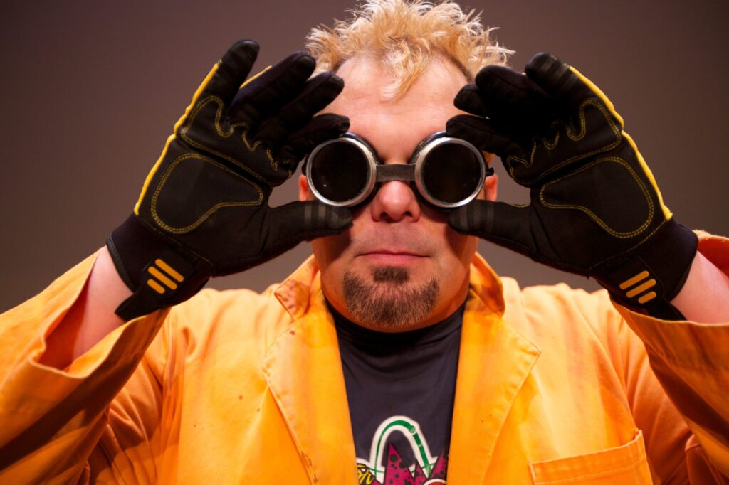 performer wearing gold jacket, gloves and goggles